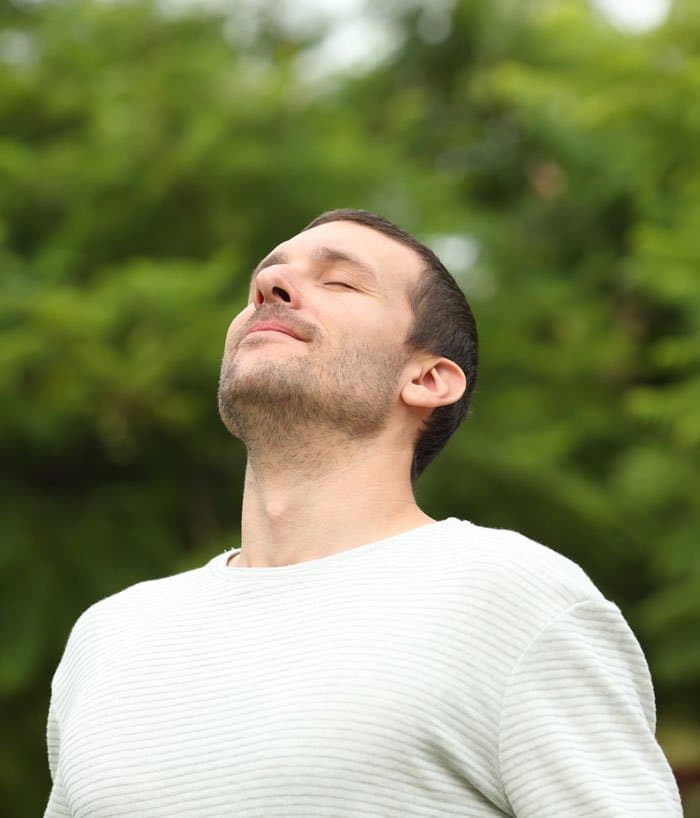 Relaxed adult man breathing fresh air in a forest