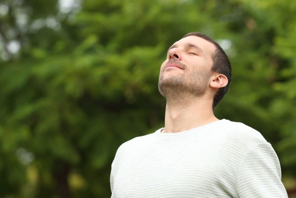 Relaxed adult man breathing fresh air in a forest