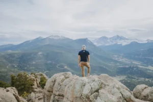 Residential vs. Outpatient Treatment - man standing on a rock with mountain view