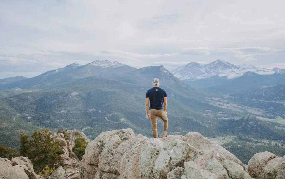 Residential vs. Outpatient Treatment - man standing on a rock with mountain view