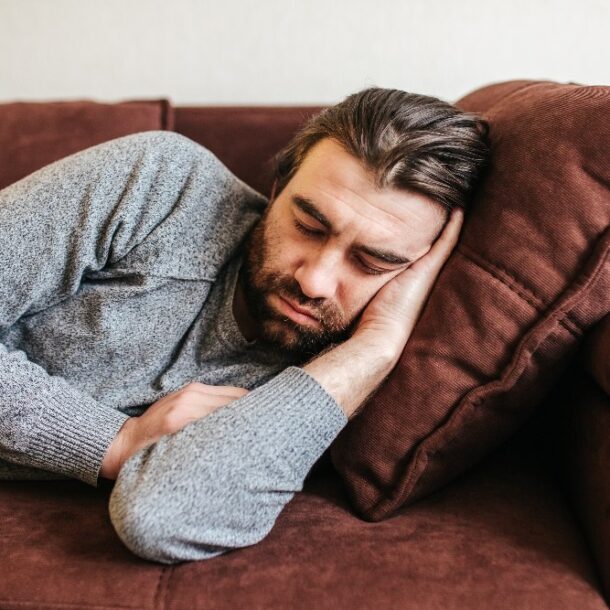 guy sleeps on the sofa in the living room after party. Concept of after party, tired overworked person hard day, lack of energy, breakdown