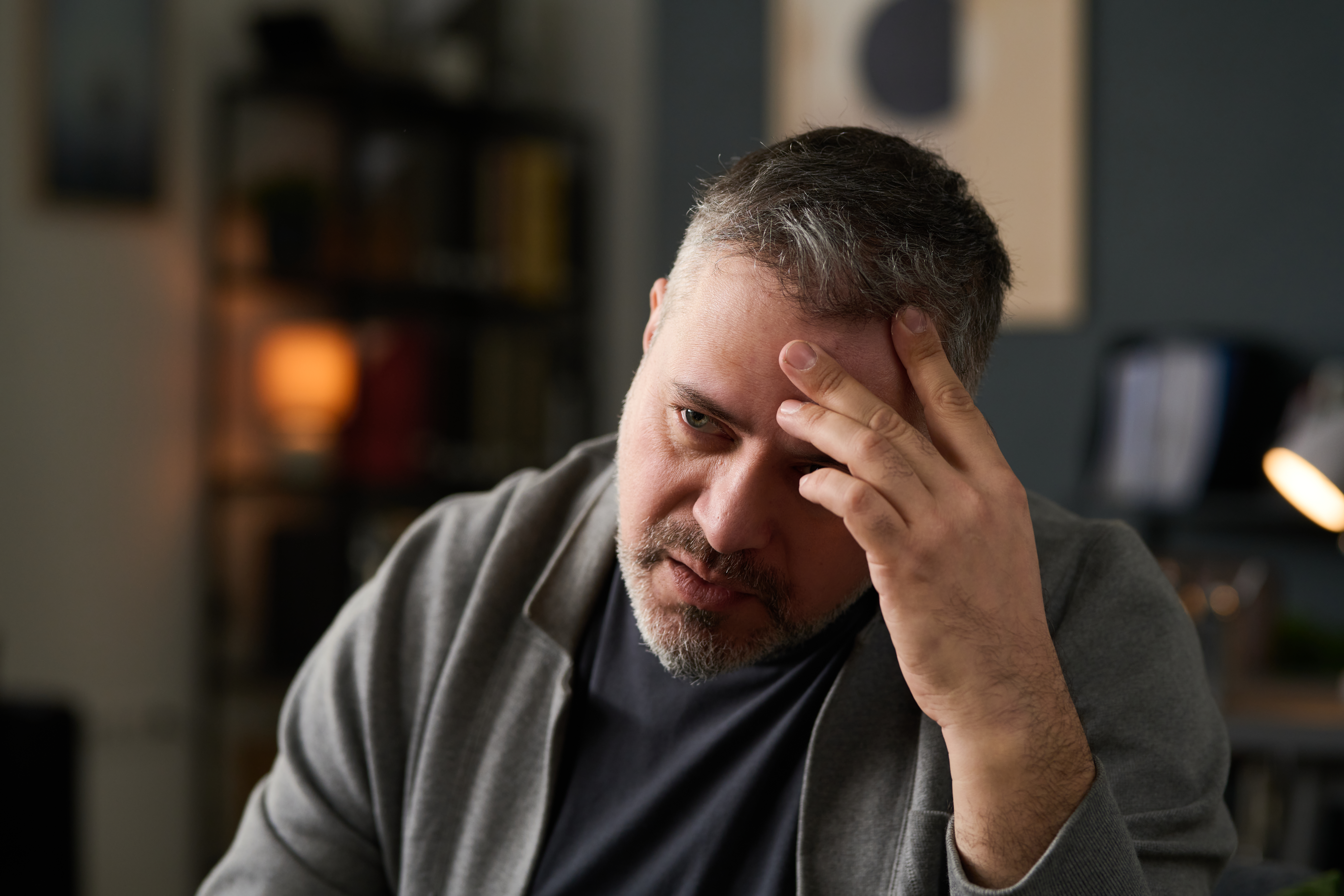 A man with a hand on his forehead looking stressed wondering what are the signs of drug addiction in men.