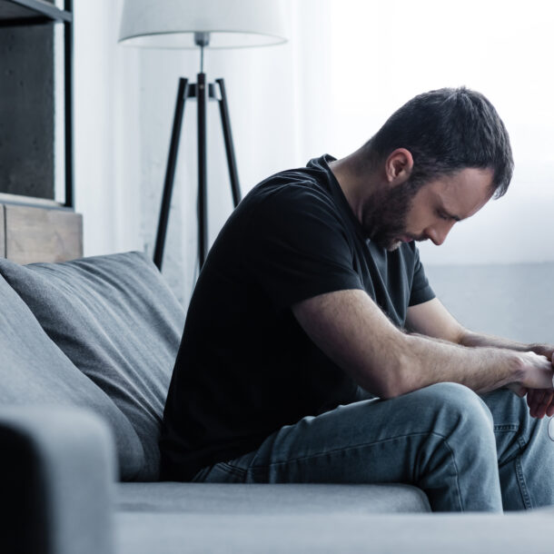 A man with his head down looking sad wondering how long does it take to break an addiction.