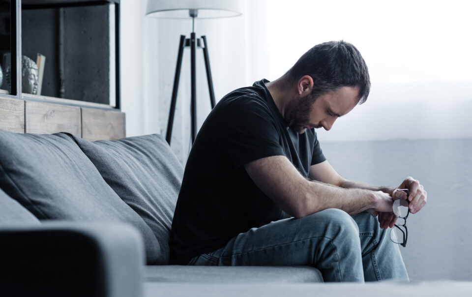 A man with his head down looking sad wondering how long does it take to break an addiction.